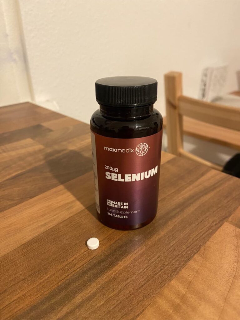 Bouteille de sélénium posée sur une table en bois, avec un comprimé blanc posé devant. Le produit est photographié en situati...