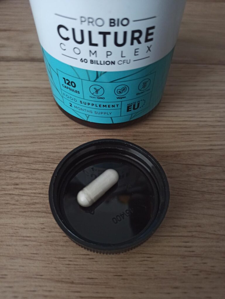 Une gélule de probiotiques WeightWorld posée sur le couvercle de la bouteille, avec la bouteille en arrière-plan.