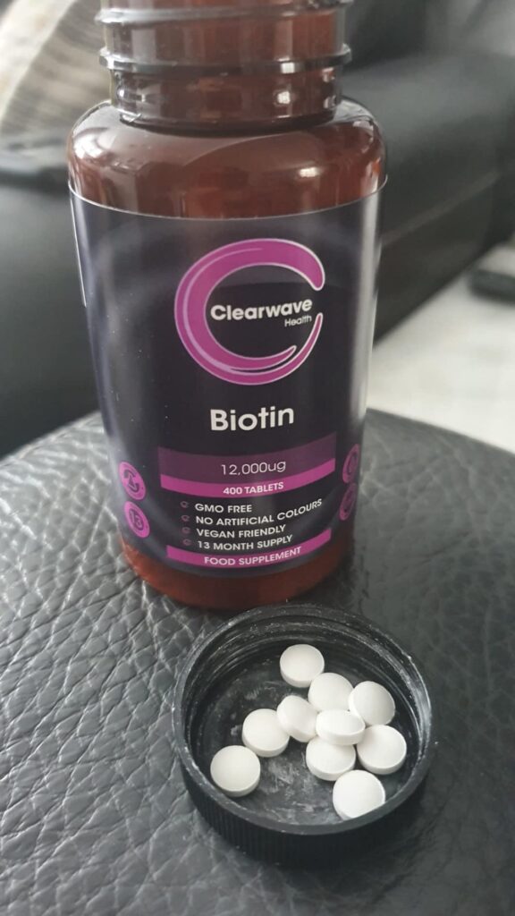 Flacon de biotine avec son couvercle rempli de comprimés.