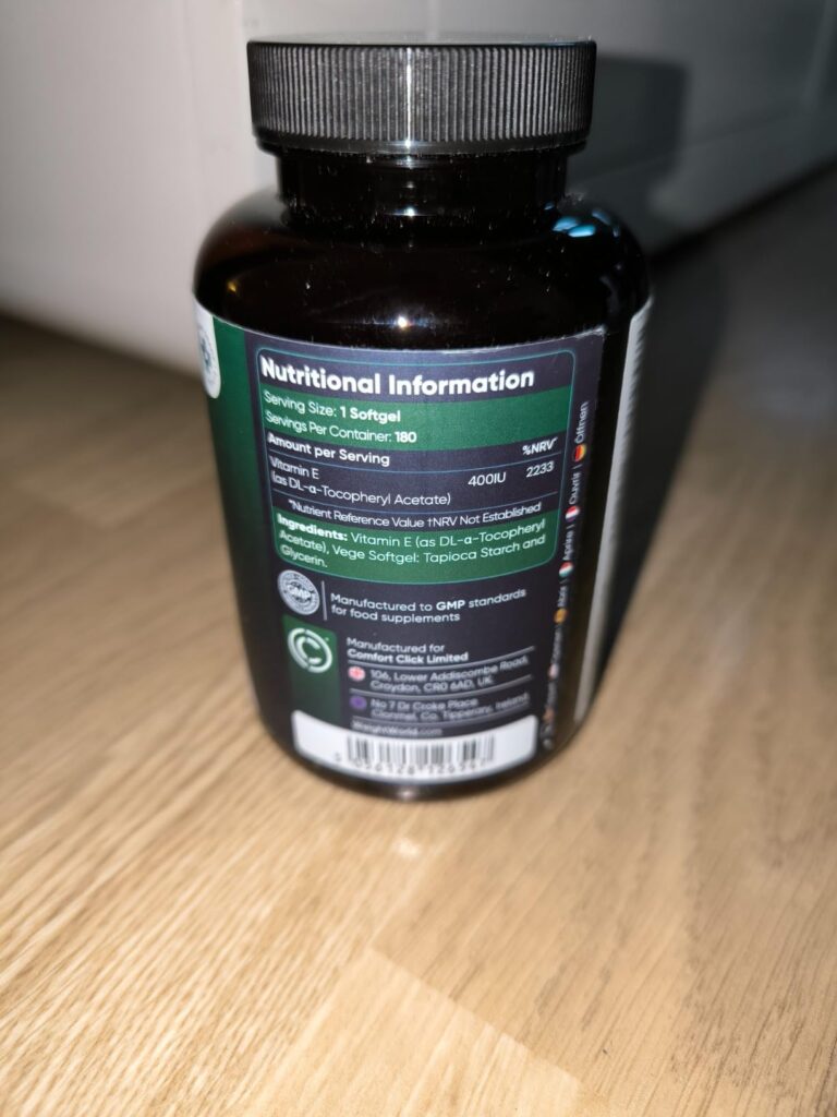 Flacon de vitamine E sur fond de parquet, avec les informations nutritionnelles de l'arrière visibles