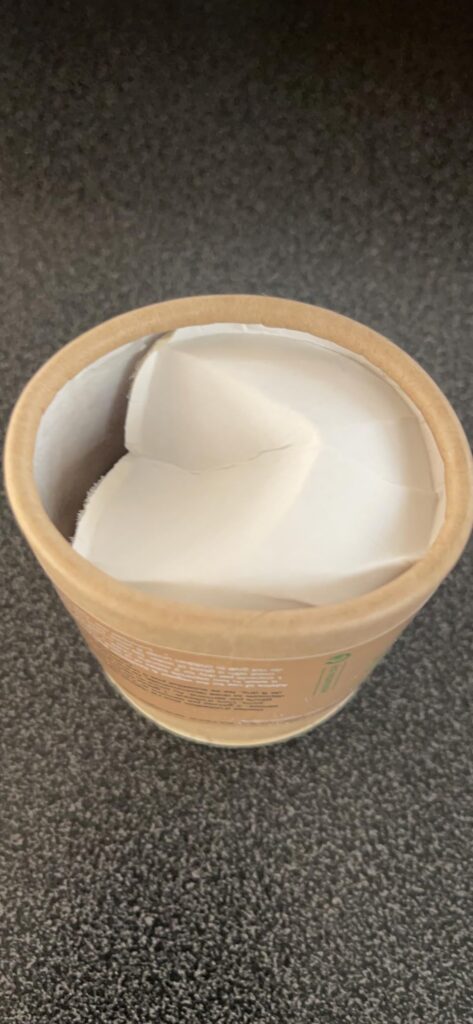 L'intérieur du pot en carton, avec le papier de calage. Le pot est posé sur une surface sombre.