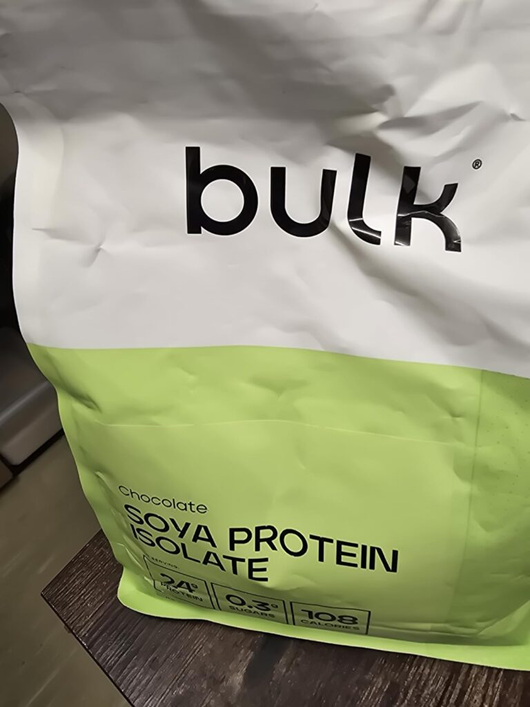 Vue en plongée sur le paquet de protéines de la marque Bulk, saveur chocolat, posé sur une table en bois.