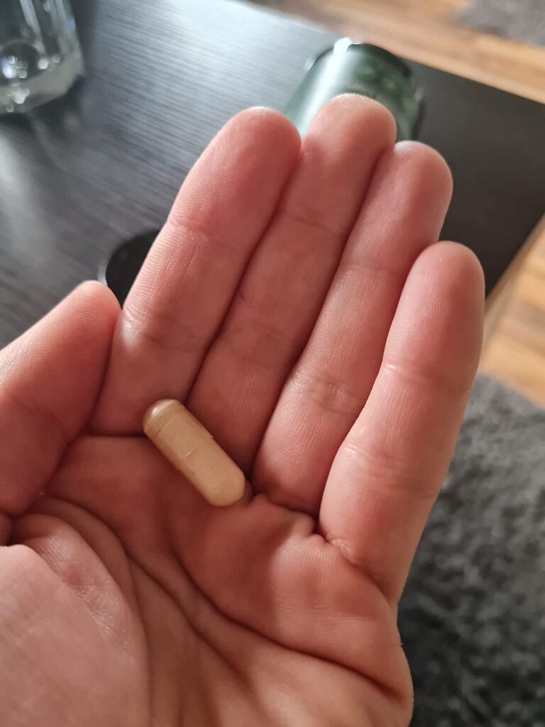 Une seule gélule dans la paume d'une main, mise en situation.