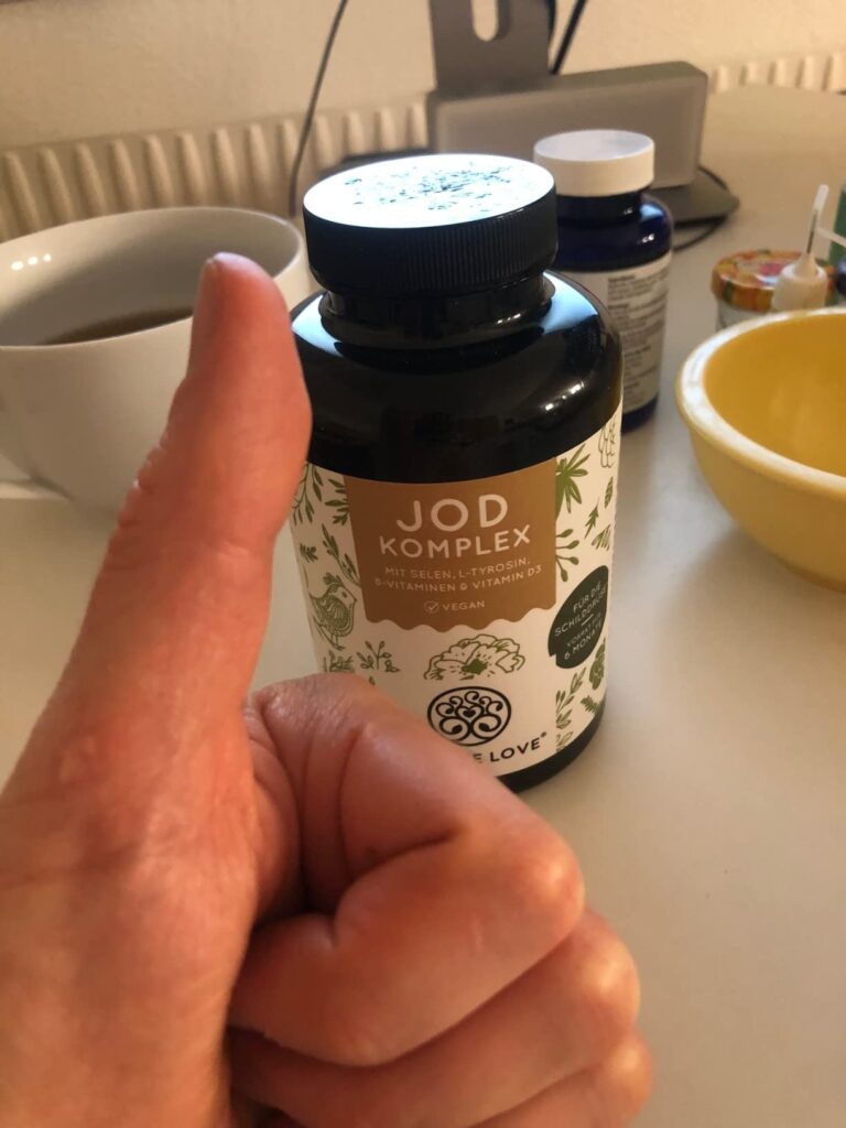 Flacon de Jod Komplex tenu en main, avec un pouce levé en signe d'approbation.