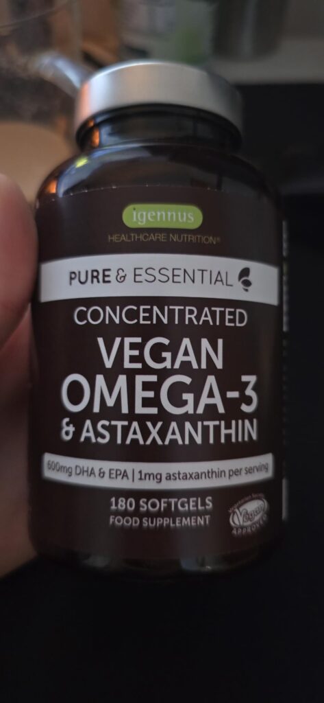 Flacon de gélules OMEGA-3 tenu à la main, avec l'étiquette bien visible.