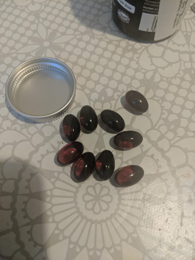 Gélules éparpillées sur une surface, avec le couvercle du flacon à côté.