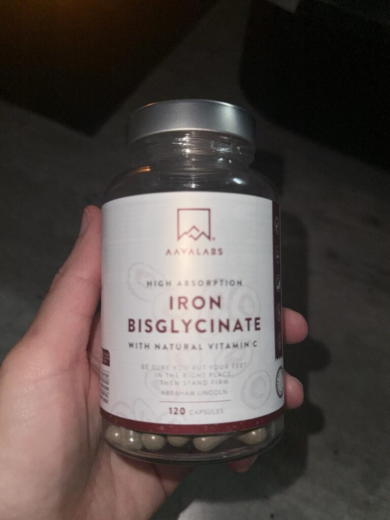Bouteille de compléments alimentaires, marque Naturelo, tenue dans une main, avec l'étiquette visible et le couvercle gris ar...