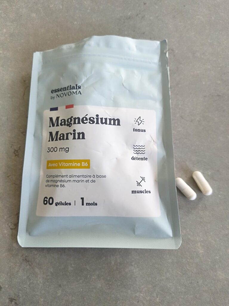 Le sachet de Magnésium Marin est posé sur une table grise, avec deux gélules sorties du sachet à côté.