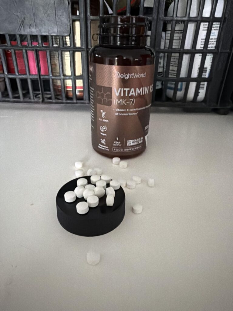 Bouteille de vitamine K2 et gélules éparpillées sur le couvercle et une table