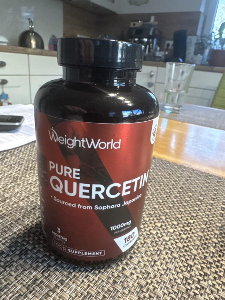 Bouteille de compléments alimentaires WeightWorld Pure Quercetin posée sur une table de cuisine, avec un arrière-plan flou de...
