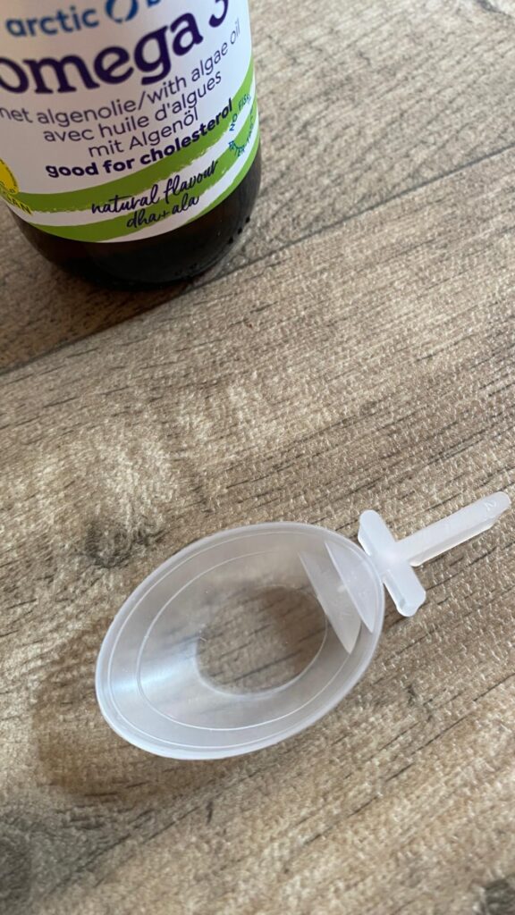 Vue de la dosette en plastique transparente et du flacon de compléments alimentaires.