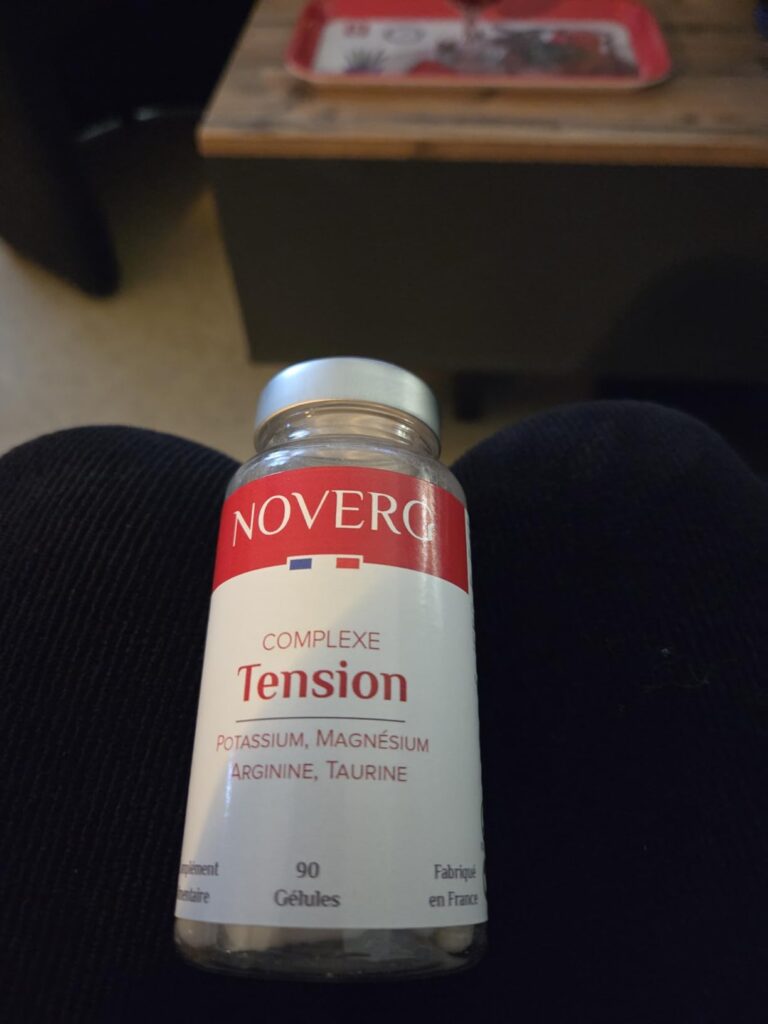 Bouteille de compléments alimentaires posée sur une jambe, en intérieur