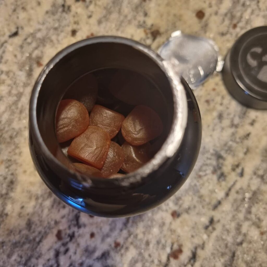 Vue de dessus du pot ouvert, montrant les bonbons à l'intérieur et le couvercle à côté.