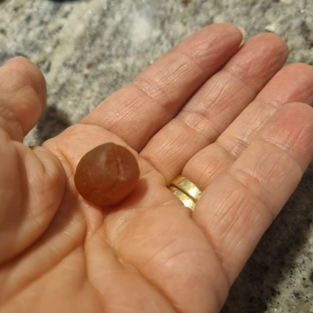 Un bonbon est présenté dans la main d'une personne, montrant sa taille et sa texture.