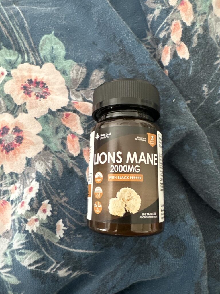 Le flacon de compléments alimentaires posé sur un tissu à motifs floraux.