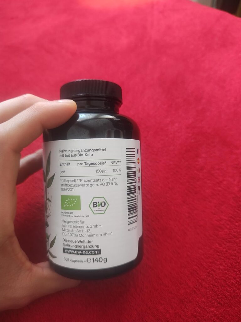 Bouteille de compléments alimentaires vue de l'arrière, tenue par une main. L'étiquette indique des informations nutritionnel...