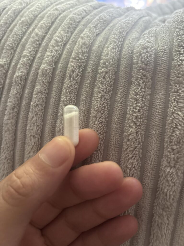Une main tient une gélule.