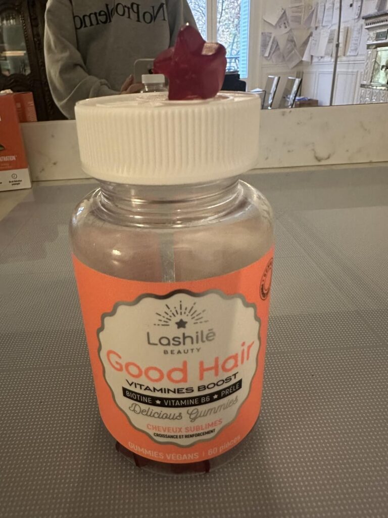 Le flacon de gummies posé sur un plan de travail, avec un gummy violet sur le couvercle. Le fond montre une cuisine ou une sa...