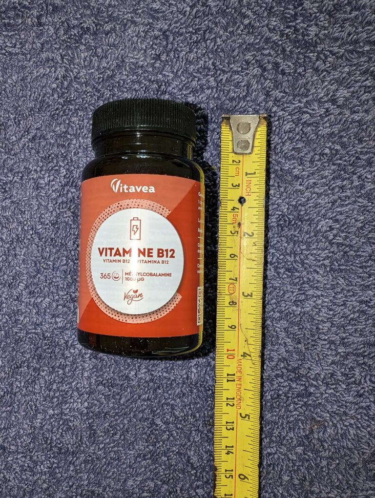 Flacon de vitamine B12 posé à côté d'un mètre-ruban, vue de face.