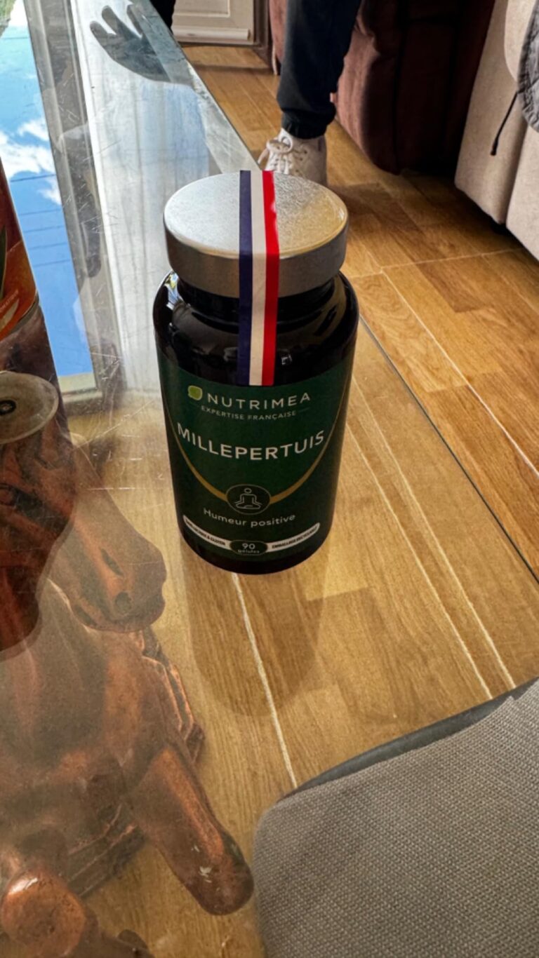 Flacon de Millepertuis Nutrimea sur une table basse, avec un ruban bleu-blanc-rouge sur le couvercle.