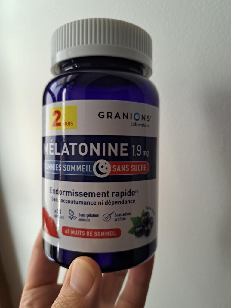 Flacon de mélatonine tenu à la main, vue de face légèrement en plongée.