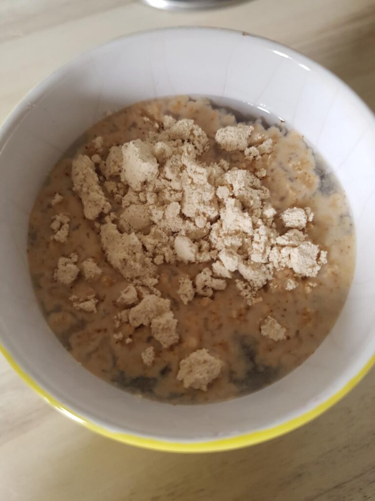 Un bol de porridge avec des morceaux de protéines vegan saveur café glacé. Les flocons ont l'air d'être des flocons d'avoine,...