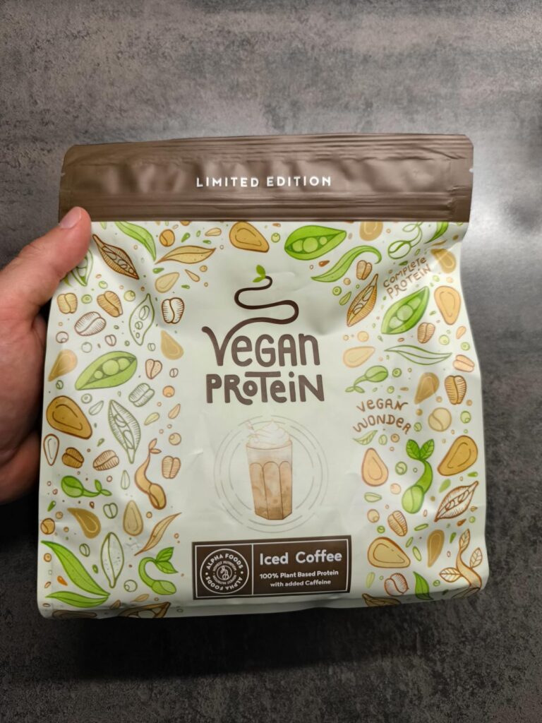 Vue du paquet de protéines vegan saveur café glacé tenu par une main. Il s'agit du même produit que le visuel 0, mais avec la...