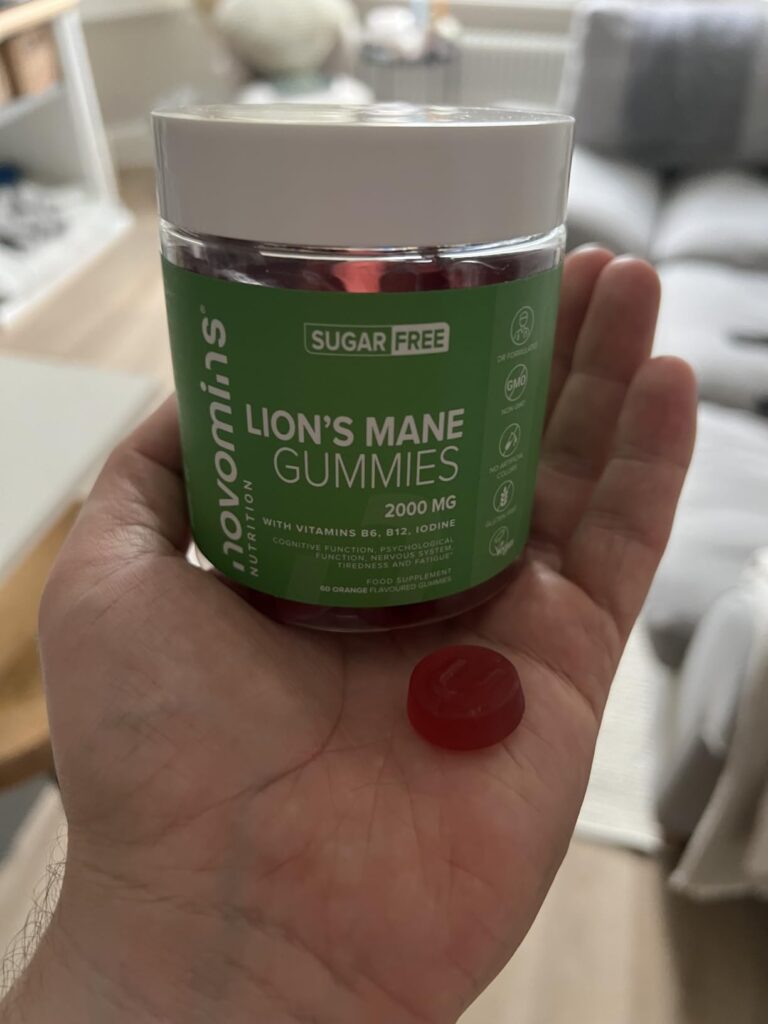 Un pot de Novomins Lion's Mane Gummies tenu dans une main, avec un gummy posé dans la paume.