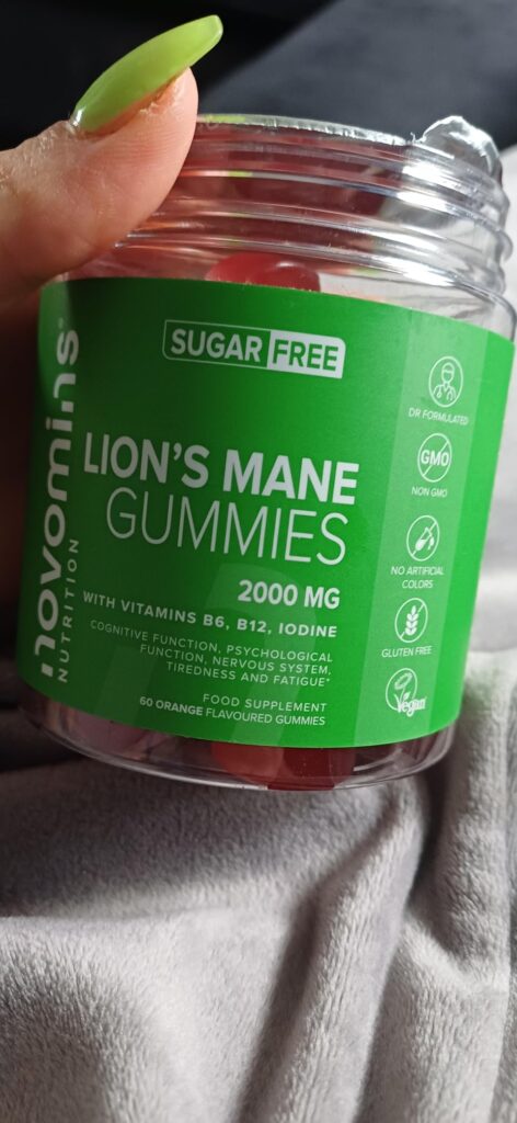 Un pot de Novomins Lion's Mane Gummies tenu dans une main, montrant l'étiquette et les certifications.