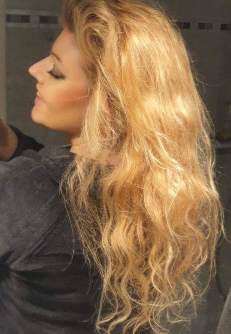 Une femme de profil, les cheveux longs, blonds et ondulés.
