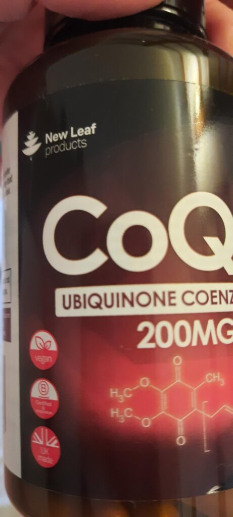 Gros plan sur l'étiquette de la bouteille de compléments alimentaires CoQ10, avec des symboles de certification et la formule...
