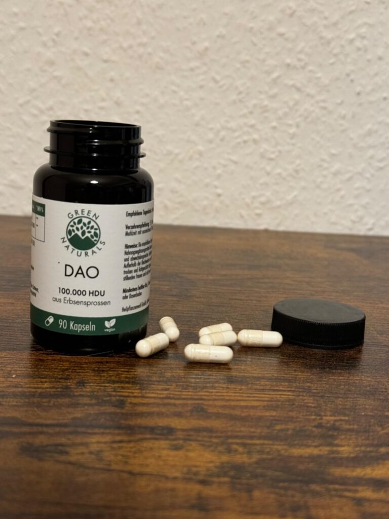 Flacon de capsules DAO ouvert, avec des capsules dispersées sur une surface en bois à côté du bouchon.