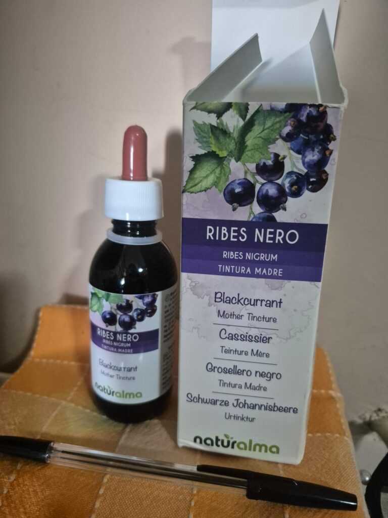 Le packaging ouvert avec la bouteille et son compte-gouttes. Un stylo est posé devant la boîte pour donner une échelle.