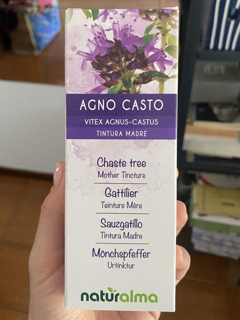 Boîte de teinture mère Agno Casto tenue dans une main, arrière-plan flou.