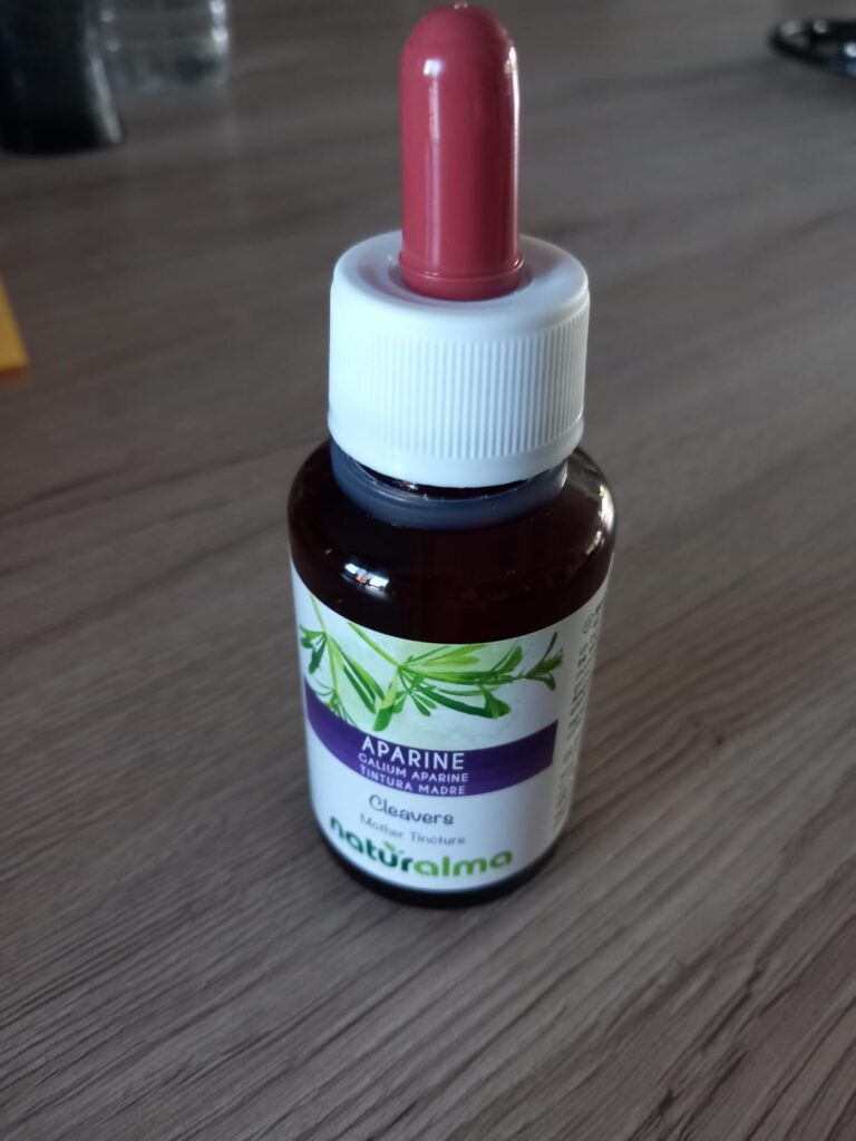 Flacon de teinture mère d'Apparine sur une table en bois.