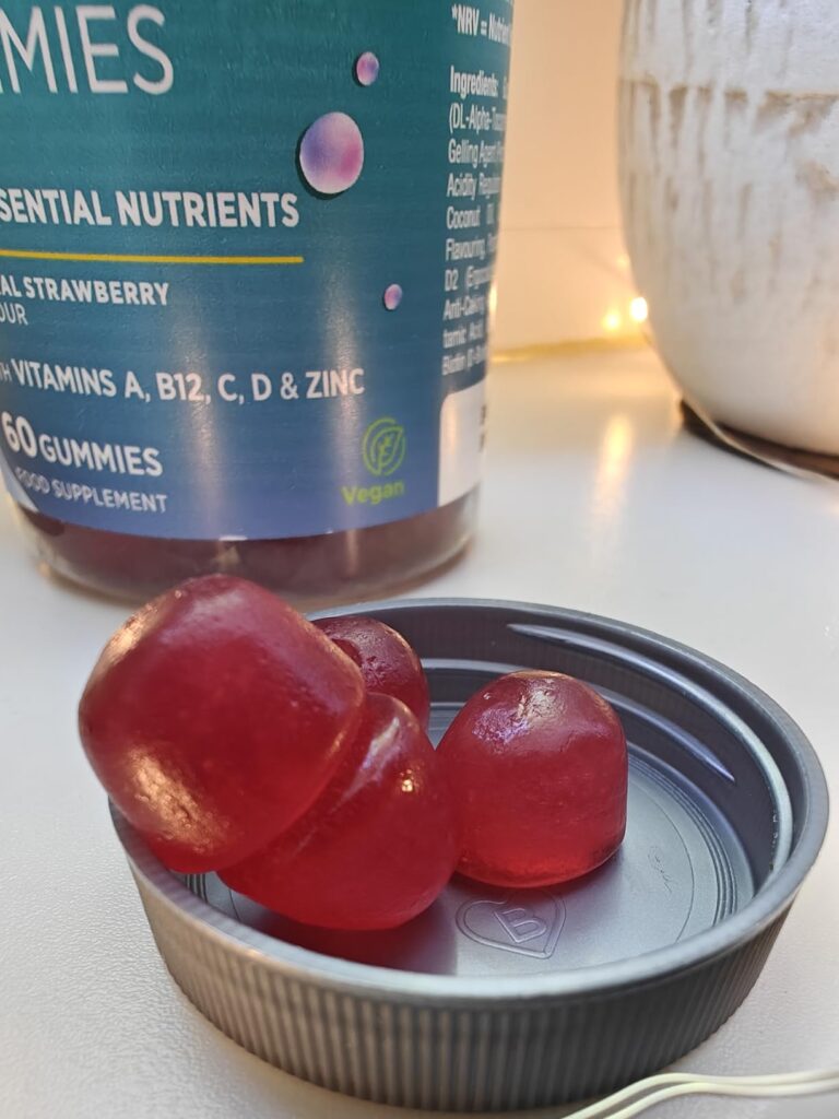 Gros plan sur le couvercle d'un pot de vitamines en gomme, avec trois gommes à l'intérieur, le pot étant en arrière-plan flou...