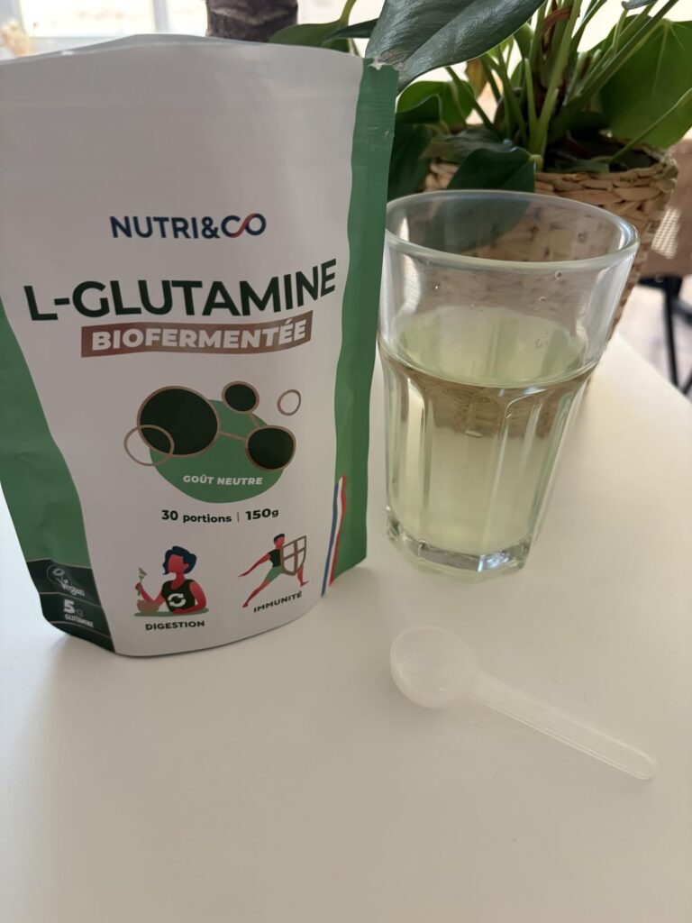Sachet de L-Glutamine de la marque Nutri&Co, avec un verre d'eau et une cuillère doseuse.