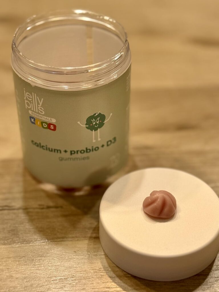 Pot de Jelly Pills Kids ouvert, avec un gummy posé sur le couvercle.