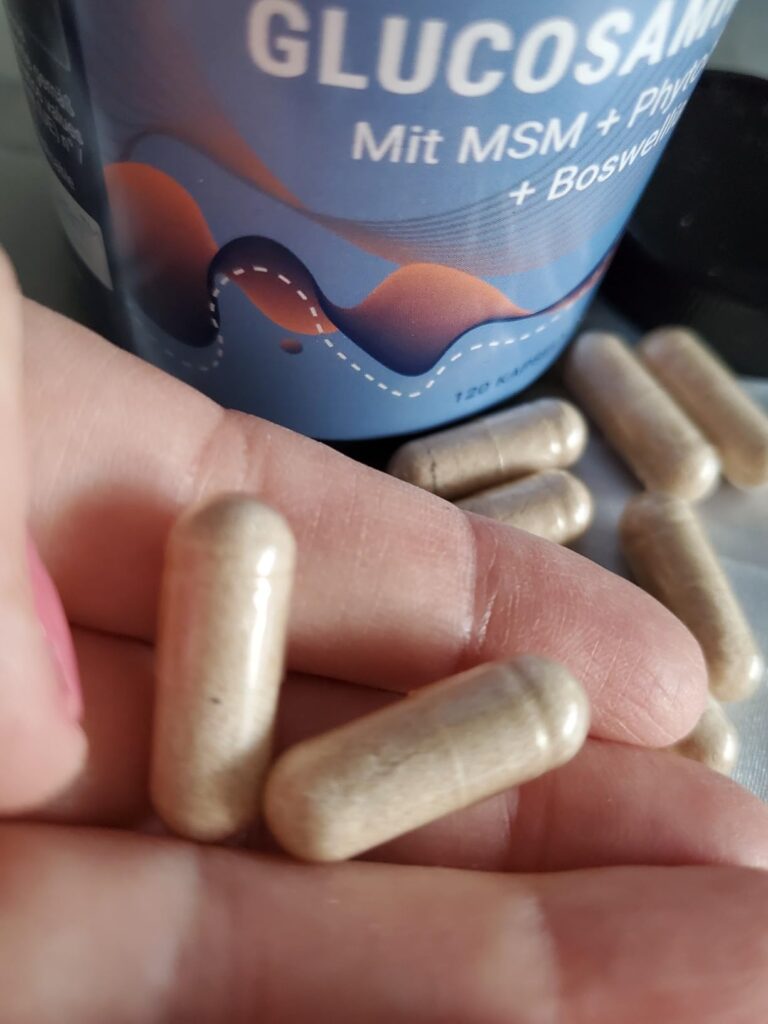 Gélules de glucosamine posées dans la main, avec le pot en arrière-plan. Similaire au visuel 1.