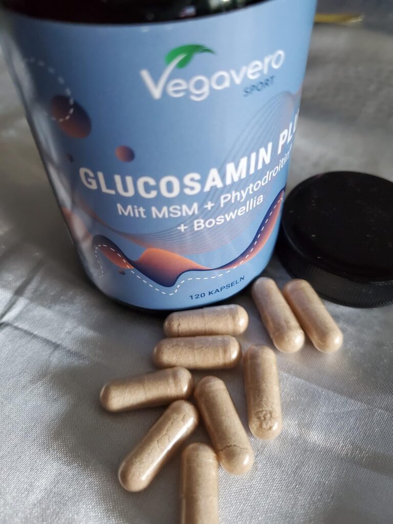 Gélules de glucosamine posées sur une table à côté du pot, avec le bouchon. Similaire au visuel 0.