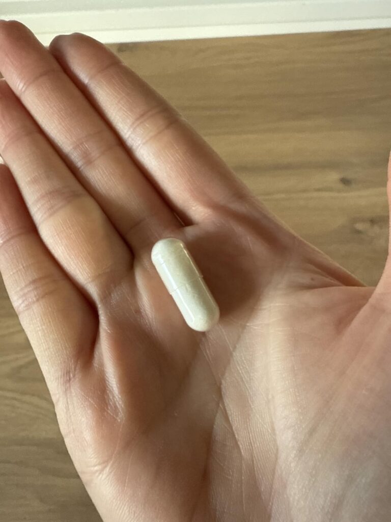 Une capsule de complément alimentaire posée dans la paume d'une main.
