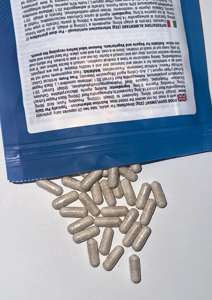 Capsules beiges répandues sur une surface claire, avec l'arrière du sachet en haut de l'image.