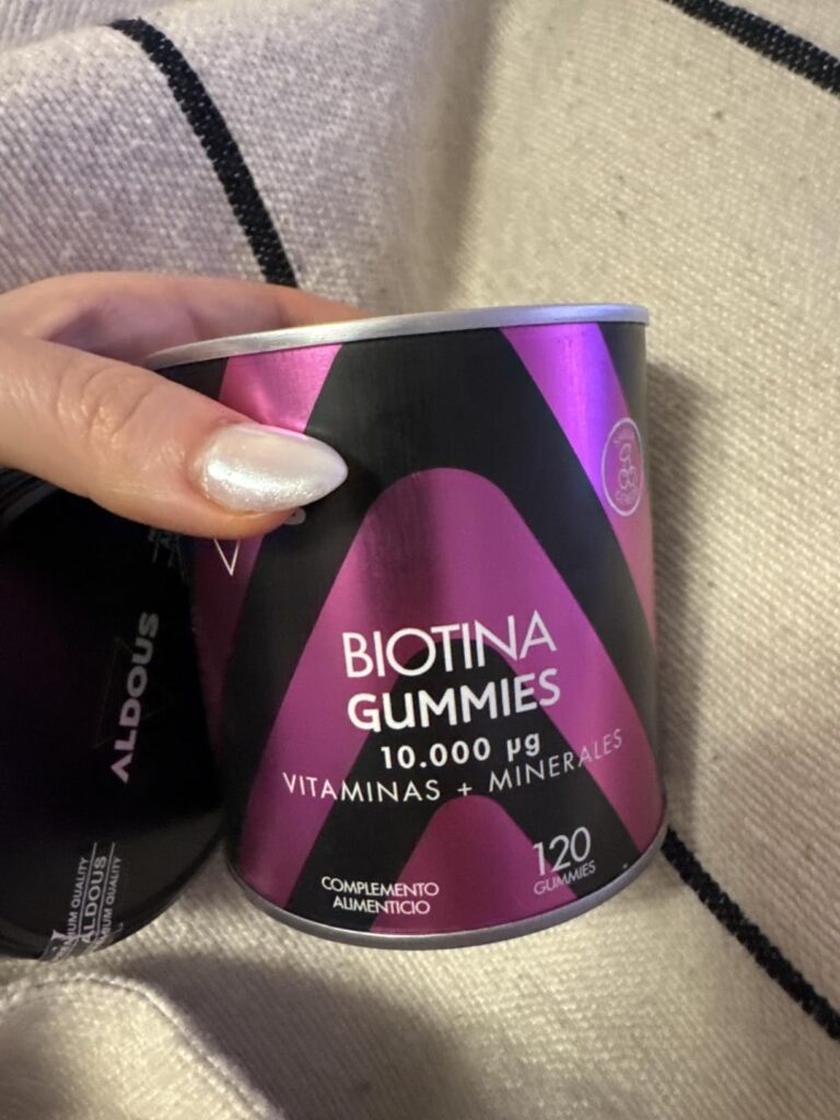 Le pot de Biotine Gummies tenu dans une main, vu de côté. On voit le texte marketing du produit.