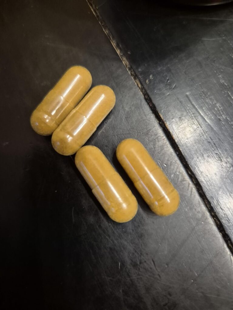 Quatre capsules sur une surface sombre.