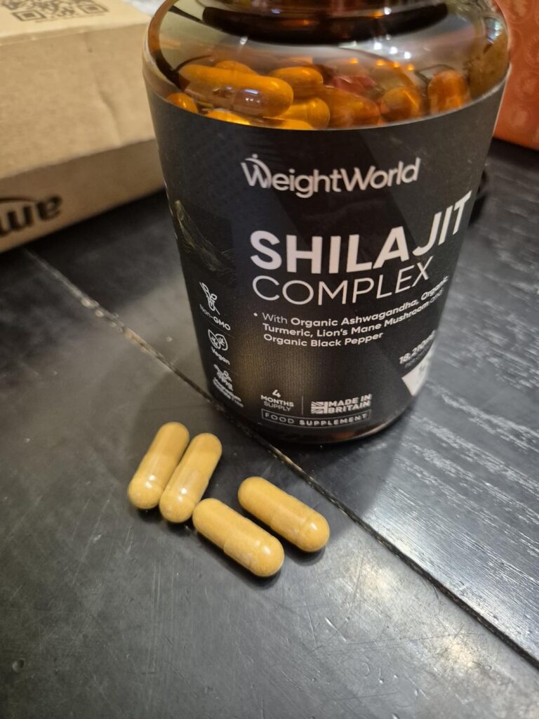 Bouteille de compléments alimentaires Shilajit Complex de WeightWorld avec quatre capsules à côté, sur une surface sombre.