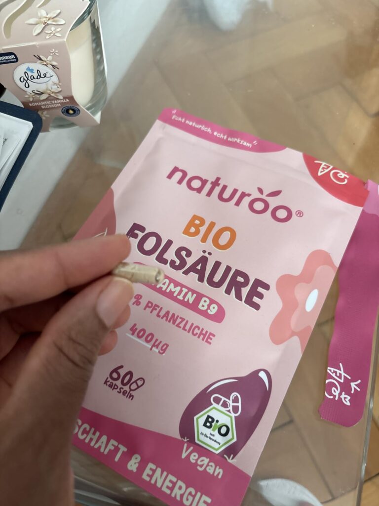 Une main tenant une capsule devant le sachet de compléments alimentaires, vue identique au visuel 0.