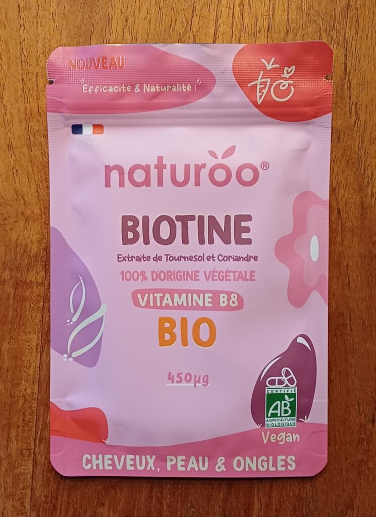 Sachet de Biotine NaturOO vue de face, sur un fond marron clair, sous un angle légèrement différent du visuel 0 et 1