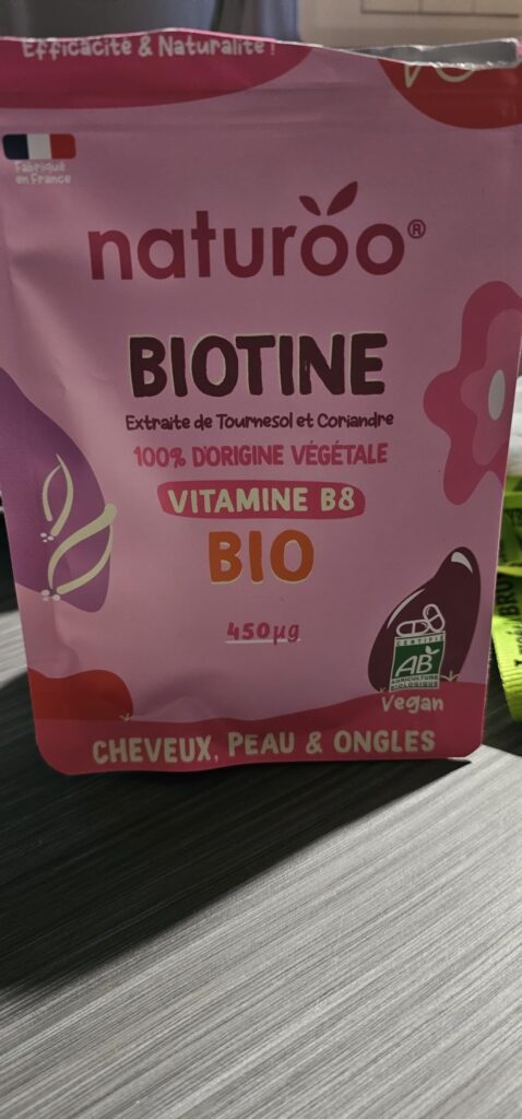 Sachet de Biotine NaturOO vue de face, sur un fond marron clair, sous un angle légèrement différent du visuel 0