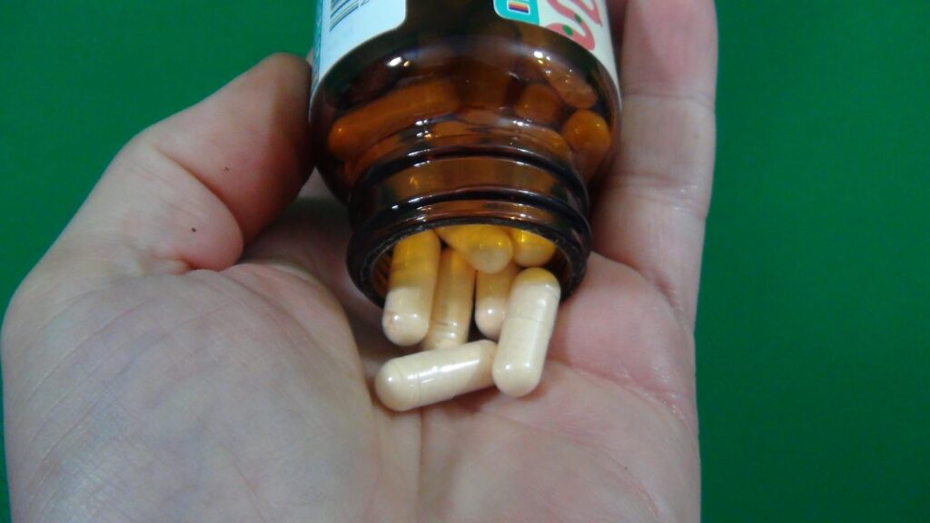 Main recevant des capsules de probiotiques qui sortent de la bouteille.