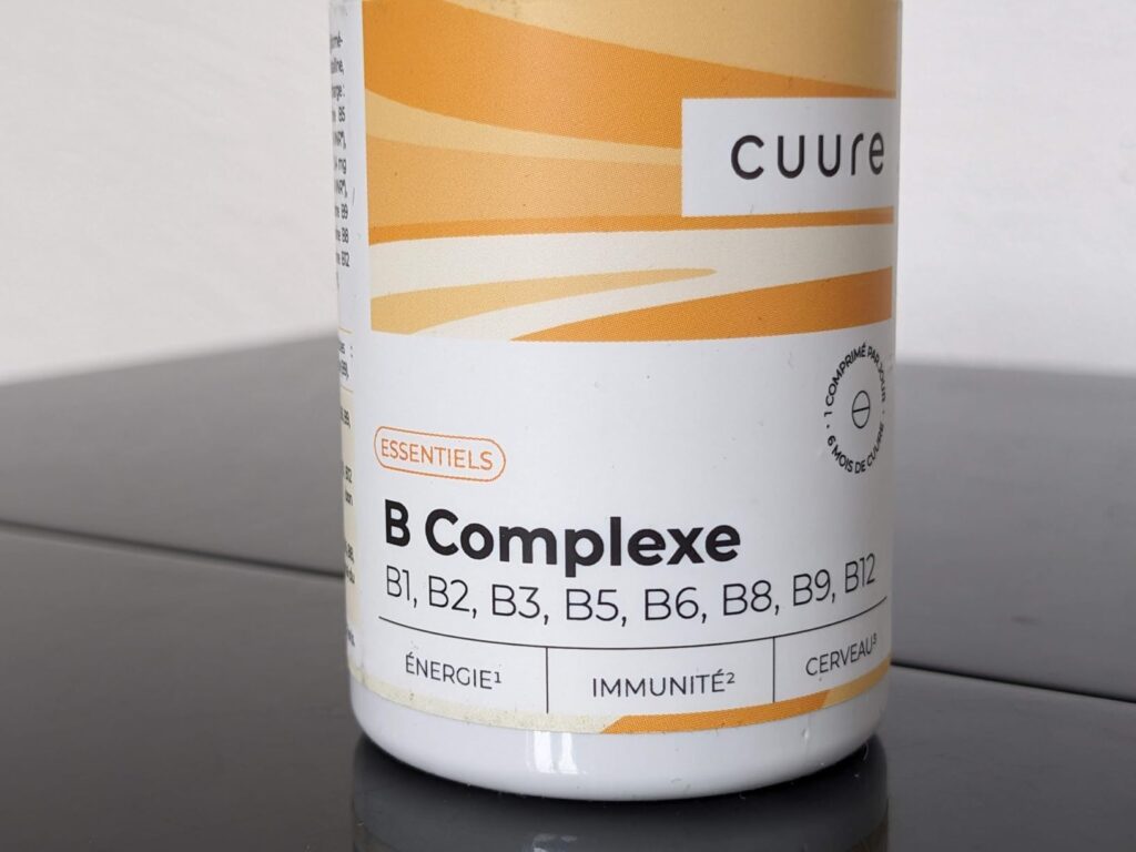 Gros plan sur l'étiquette du flacon, avec les mentions « B Complexe » et les vitamines détaillées.